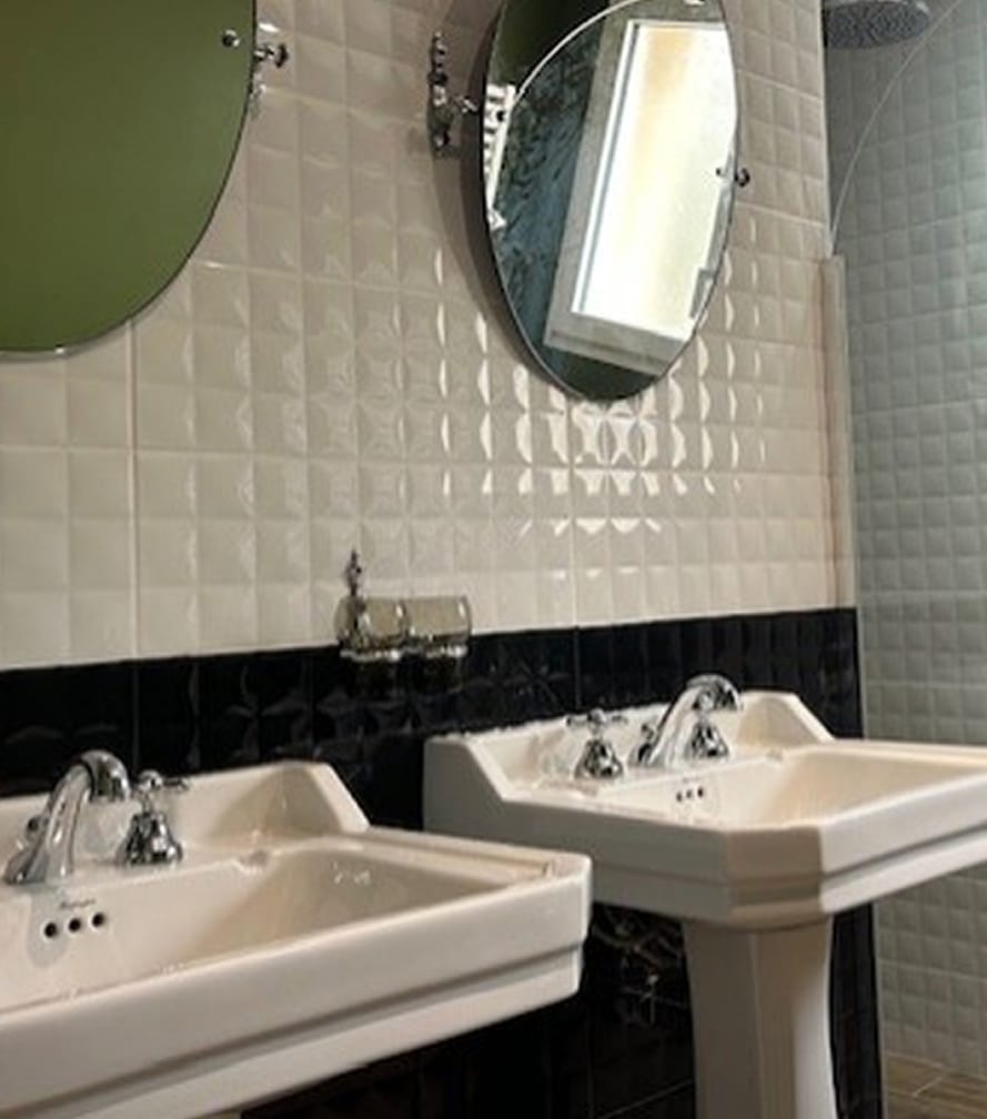 Double Vasque Salle de Bain Chic, Carrelage Noir et Blanc Salle de bain chic avec double vasque blanche sur colonnes, carrelage mural texturé blanc et noir brillant, miroirs ronds.