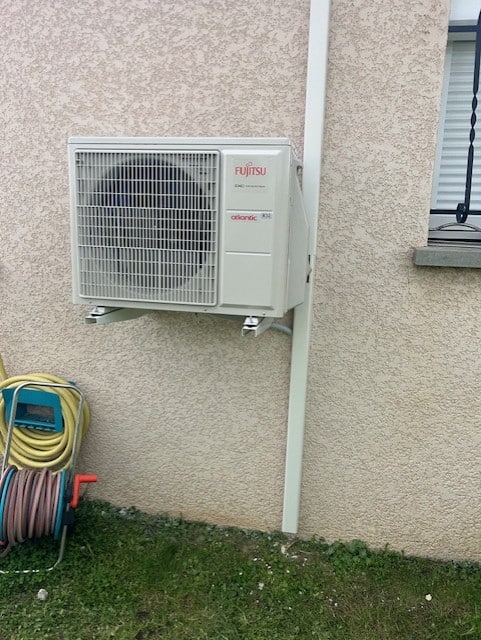 Un climatiseur blanc installé sur un mur, illustrant l'efficacité d'une installation de pompe à chaleur.