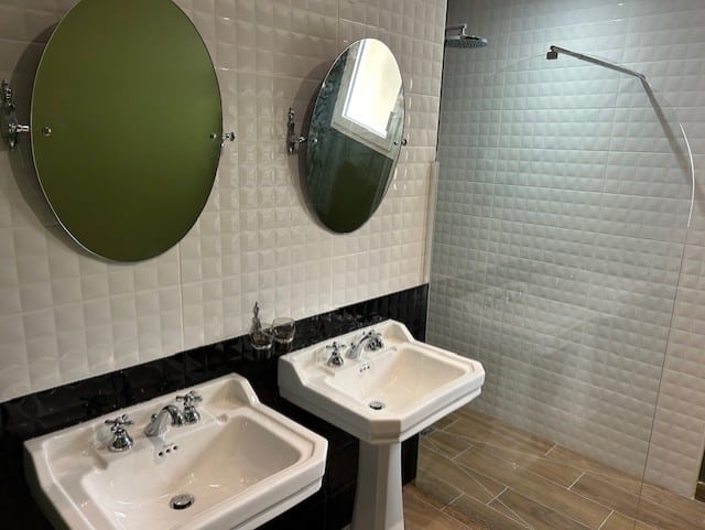 Salle de bain moderne avec deux lavabos et miroirs, mettant en avant des éléments de plomberie élégants et fonctionnels.