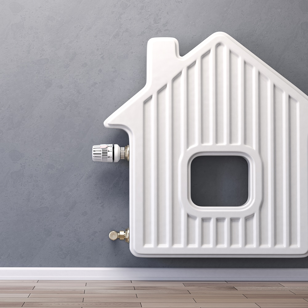 Radiateur blanc design en forme de maison avec thermostat réglé sur 3, fixé sur un mur gris texturé au-dessus d'un plancher bois.