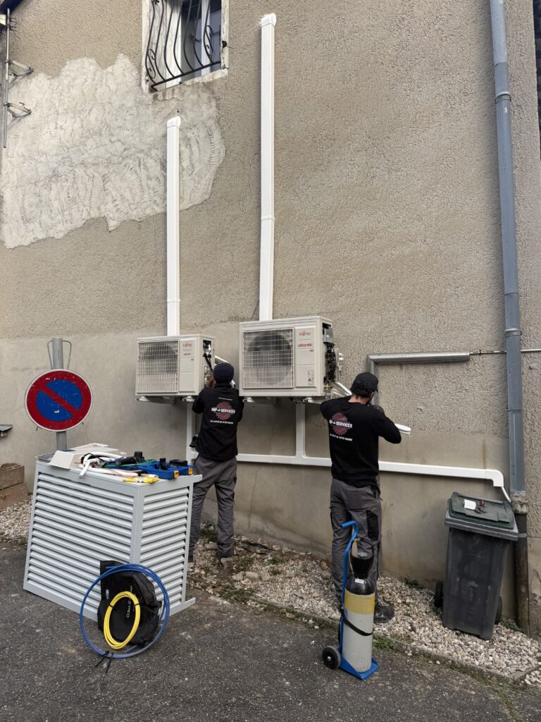 Techniciens HP-SERVICES installant deux unités de climatisation Fujitsu Atlantic sur une façade en rénovation.