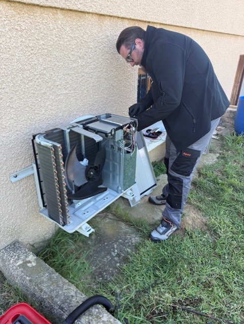 Maintenance et dépannage de climatisation par un expert Technicien chauffagiste en pleine maintenance d'une unité de climatisation extérieure ouverte sur un mur.